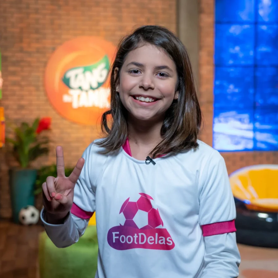 Aluna do Programa Empreendedor 5.0 no palco do Tang do Tank com a camisa do FootDelas